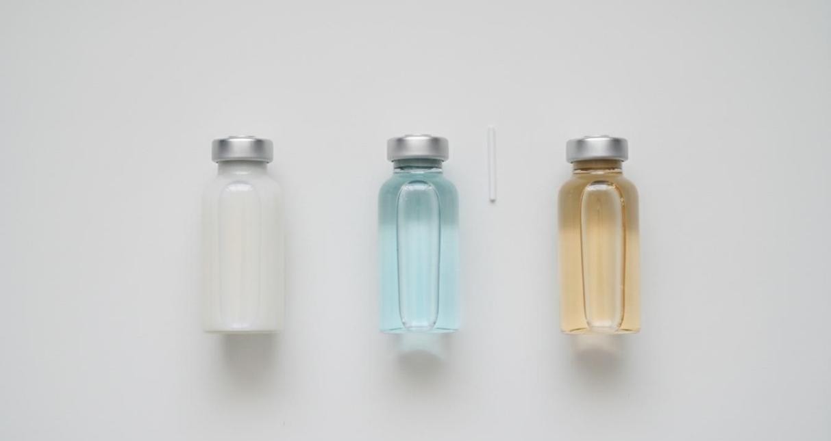 Three glass vials containing milky-white, pale blue, and amber colloidal dispersions of polymer-grafted nanoparticles on a white surface