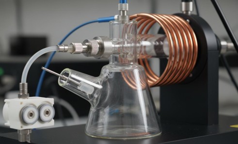 Close-up of ICP-MS sample introduction showing concentric glass nebulizer, cyclonic spray chamber, quartz torch, and RF induction coil