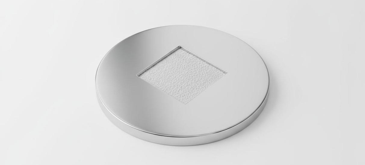 Round metallic XRD sample holder with fine white powder evenly spread in a square depression